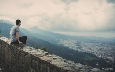 man sitting on wall looking over city
